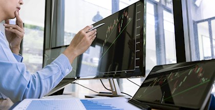 Kvinde analyserer aktier på computerskærm, lær at investere i aktier til foredrag med Gert Hansen i FOF Aarhus