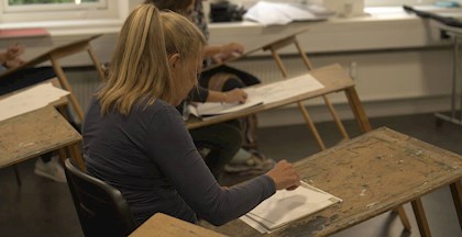 Kvinde tegner på papir med blyant, tegnekursus ved FOF Aarhus