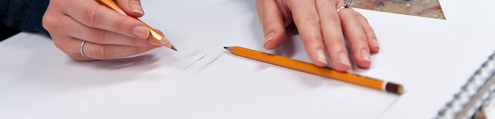 Kvinde med blyant der tegner på blankt papir på tegnekusus ved FOF Aarhus