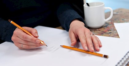 Kvinde med blyant der tegner på blankt papir på tegnekusus ved FOF Aarhus