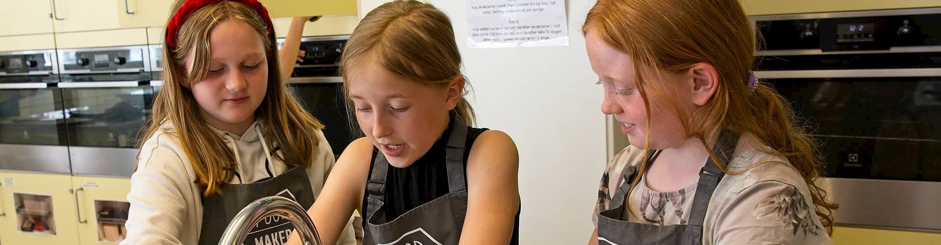 Tre piger i alderen 8.12 på madskole i FOF Aarhus' køkken.