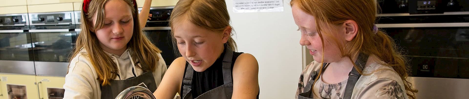 Tre piger i alderen 8.12 på madskole i FOF Aarhus' køkken.
