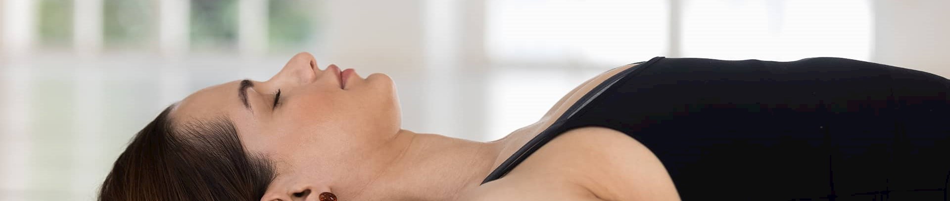 Kvinde der ligger på måtte med lukkede øjne og dyrker mindfulness, FOF Aarhus