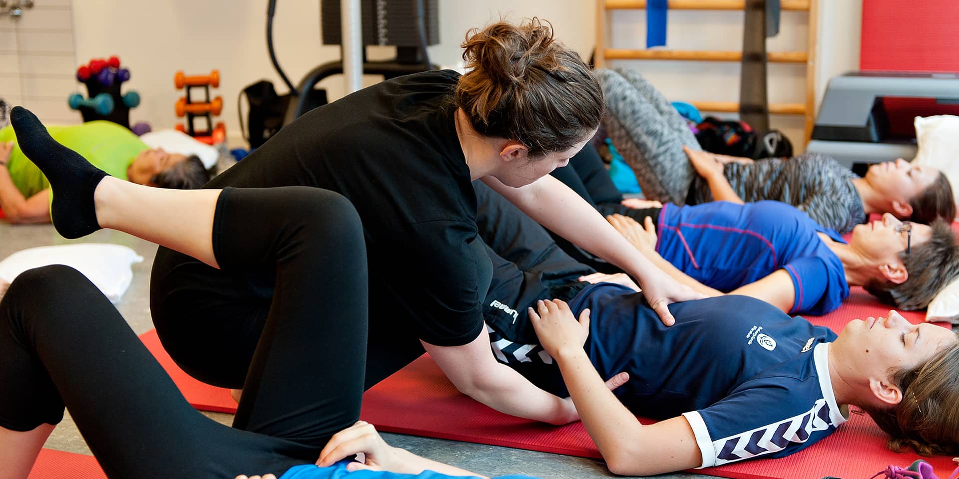 Underviser hjælper en kursist med en øvelse til pilates ved FOF Aarhus