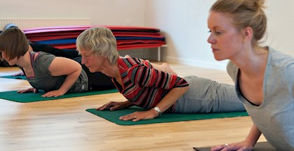 Kvinder der laver udstrækning på yogamåtte på kursus ved FOF Aarhus