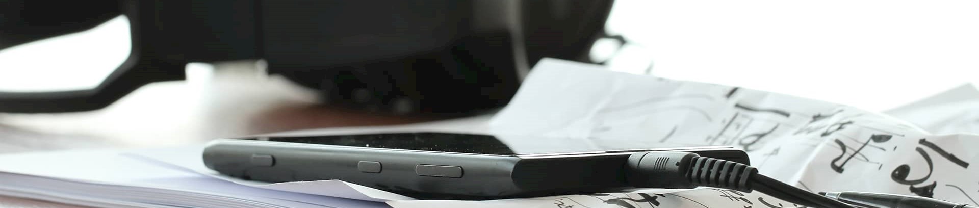 Høretelefoner, mobiltelefon og noder på papir