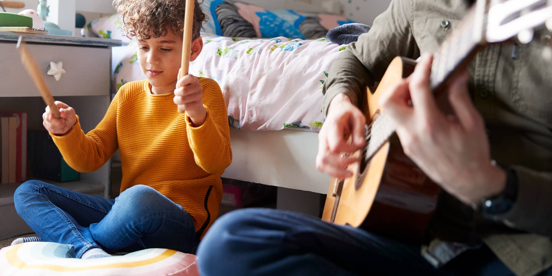 Barn og voksen som spiller musik sammen - guitar og trommestikker