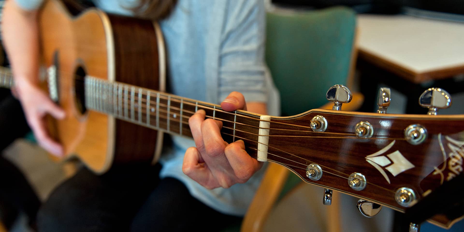 Kursist som spiller akustisk guitar ved FOF Aarhus