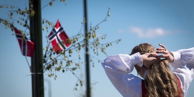 Billede af norsk pige som fletter sit hår og ser på det norske flag