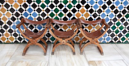 Billede af tre stole ved flisevæg i Granada, Spanien