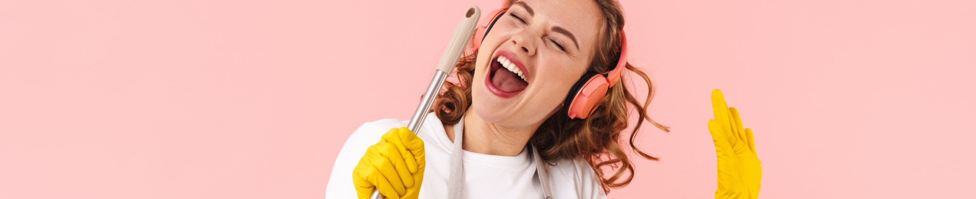 Kvinde med gule rengøringshandsker der er glad og synger