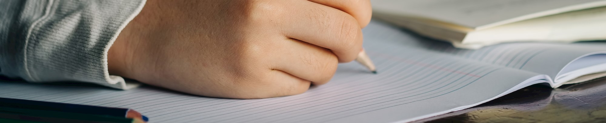 Nærbillede af hånd der skriver med blyant på papir