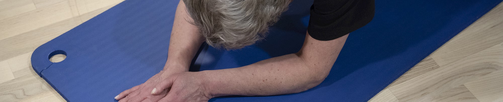 foto af kvinde der strækker ud på træningsmåtte