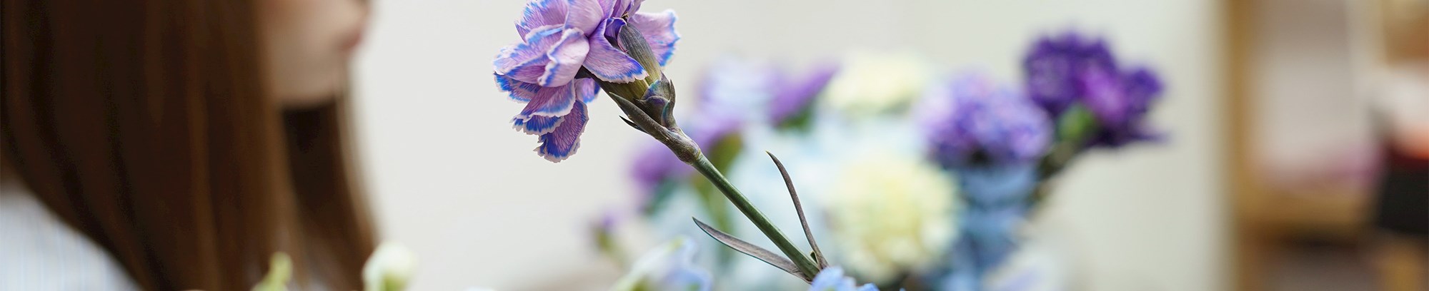 Blå og lilla blomster - med en kursist, der er ved at samle en blomsterbuket i baggrunden