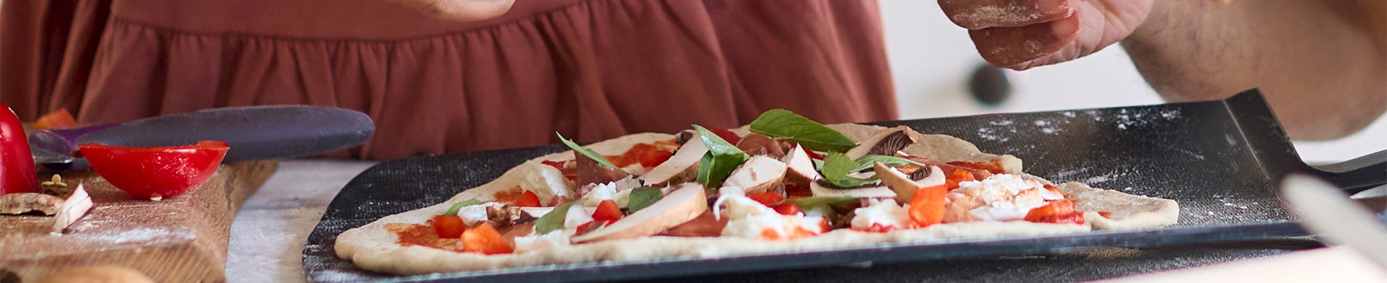To kursister tilbereder en pizza i et køkken
