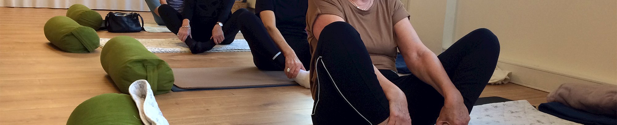 Yoga kursister, der laver stræk øvelser på yogamåtter
