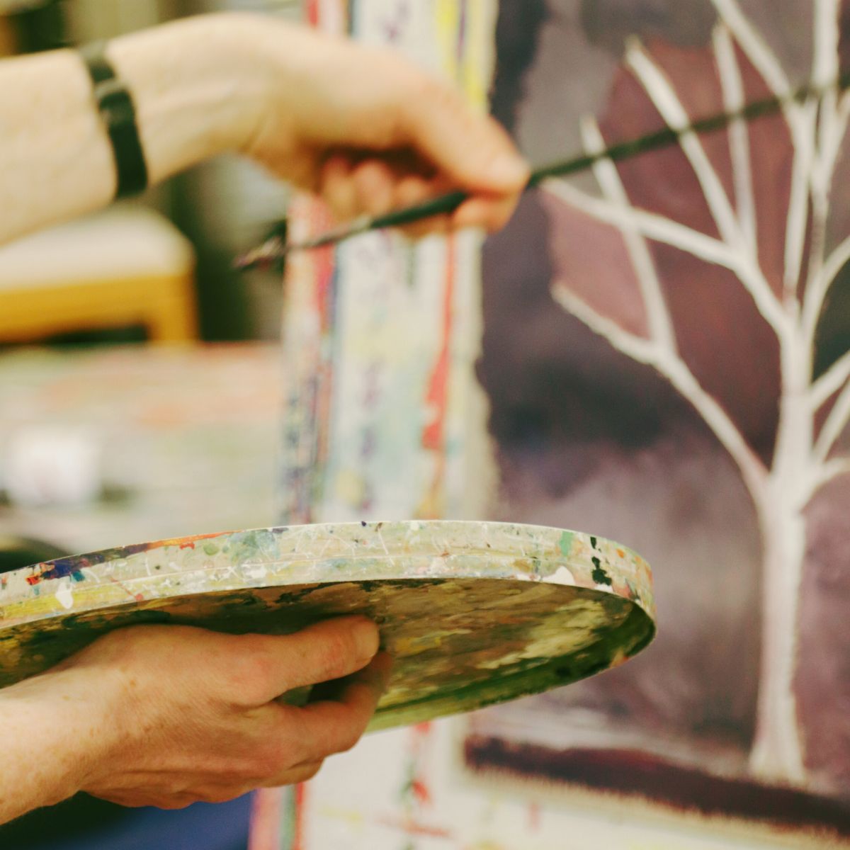 hænder i gang med at male på lærred med pensel - i Malersalen hos FOF i Randers