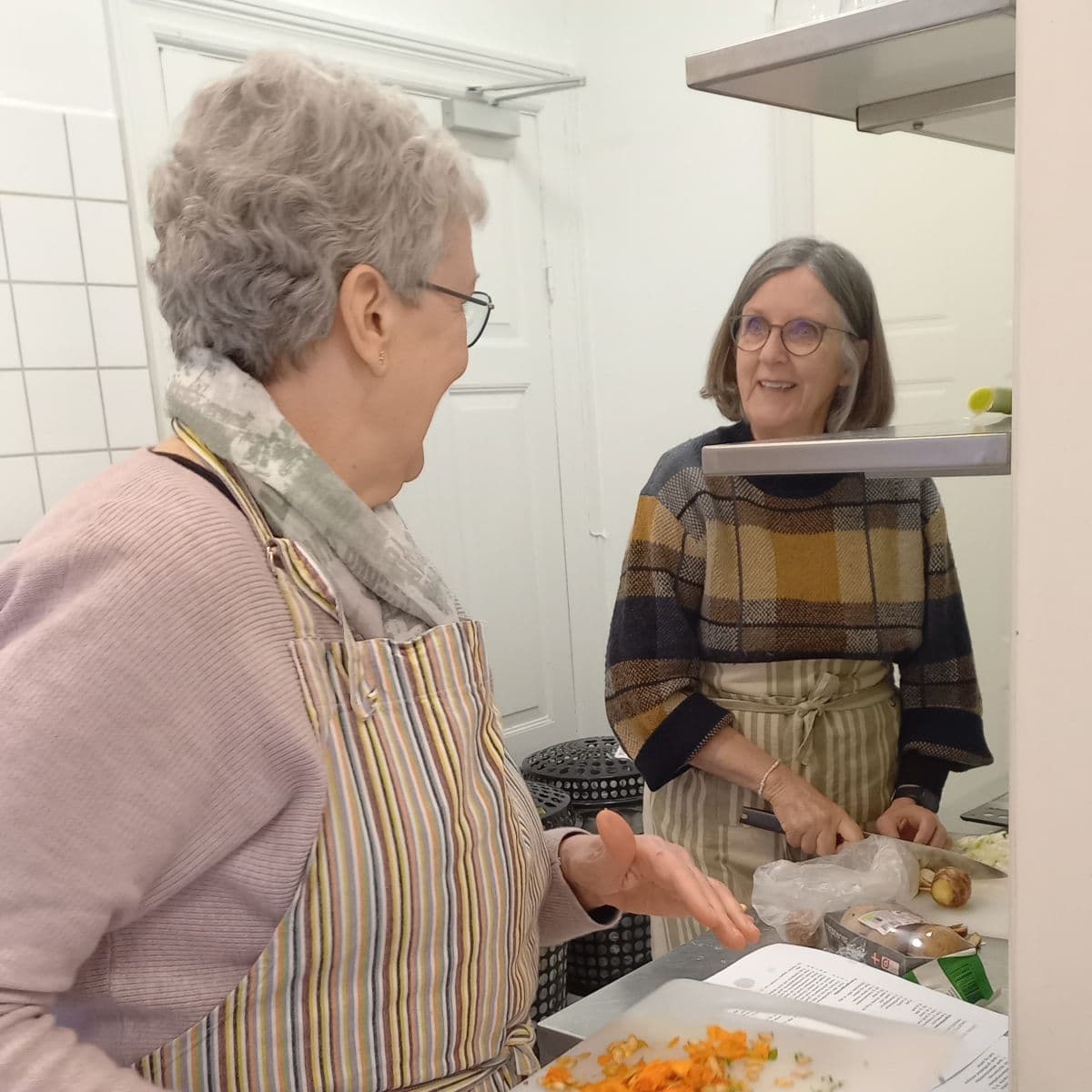 2 kursister i køkkenet smiler og laver mad - Rosenlund, FOF's bygning i Randers