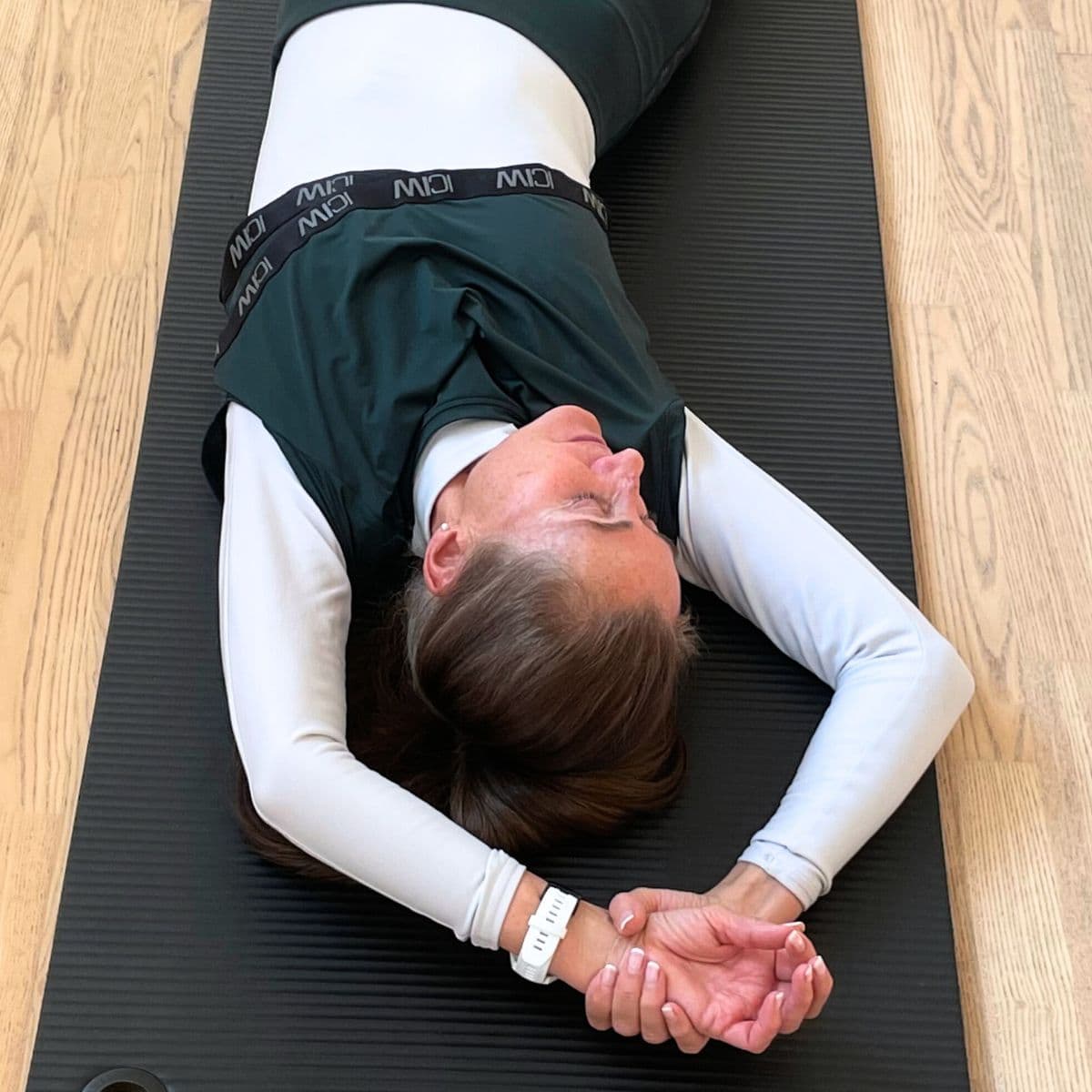 Kvinde ligger på yogamåtte