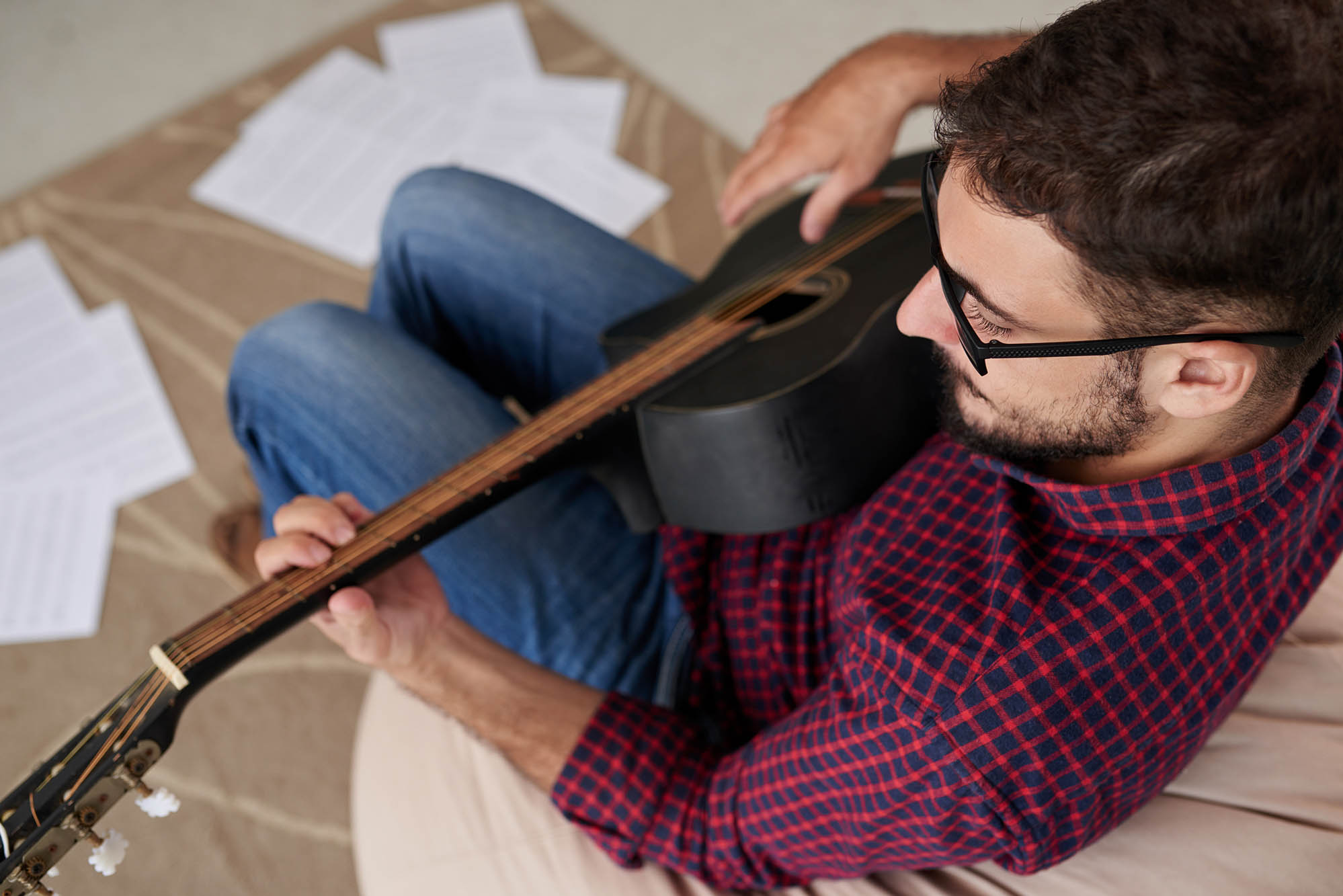 Mand med guitar skriver egne sange på sangskriverkursus