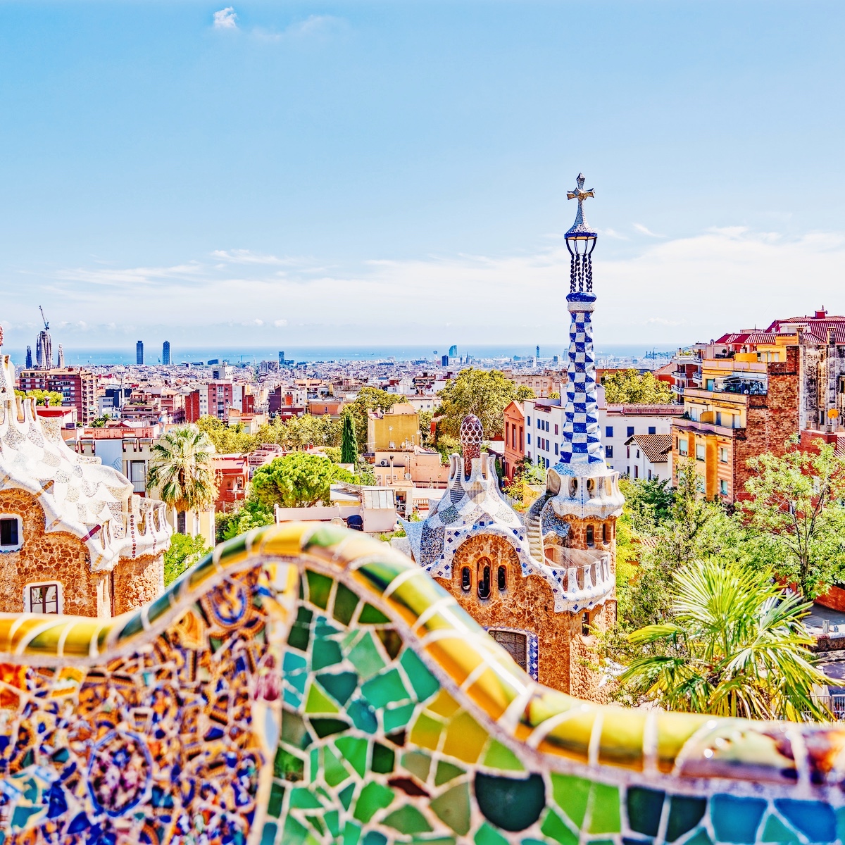 Farverigt udsyn over Barcelona fra Park Güell med Gaudís mosaikker i forgrunden.