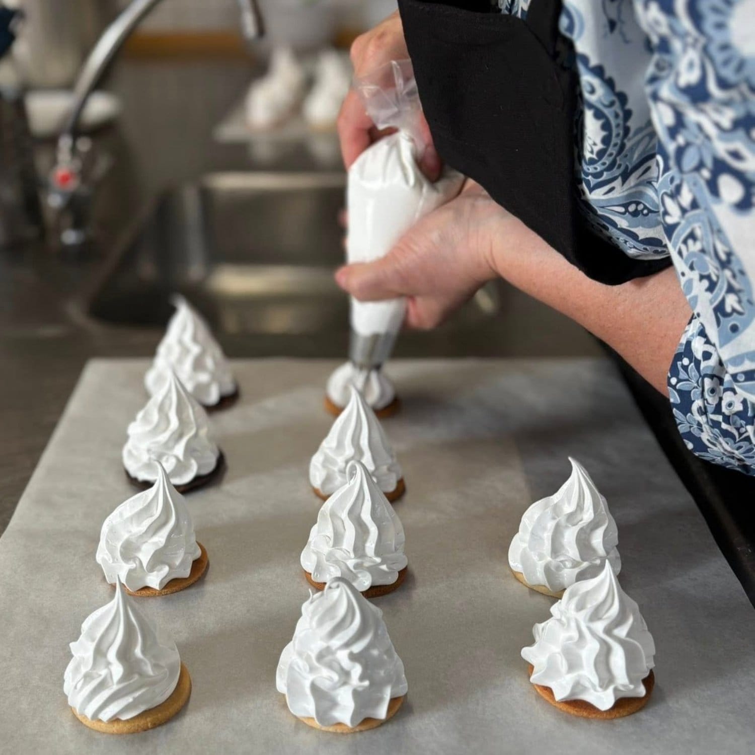 Kursist der er i gang med at pibe flødebolleskum ud på flødebollebunde på et bagepapir