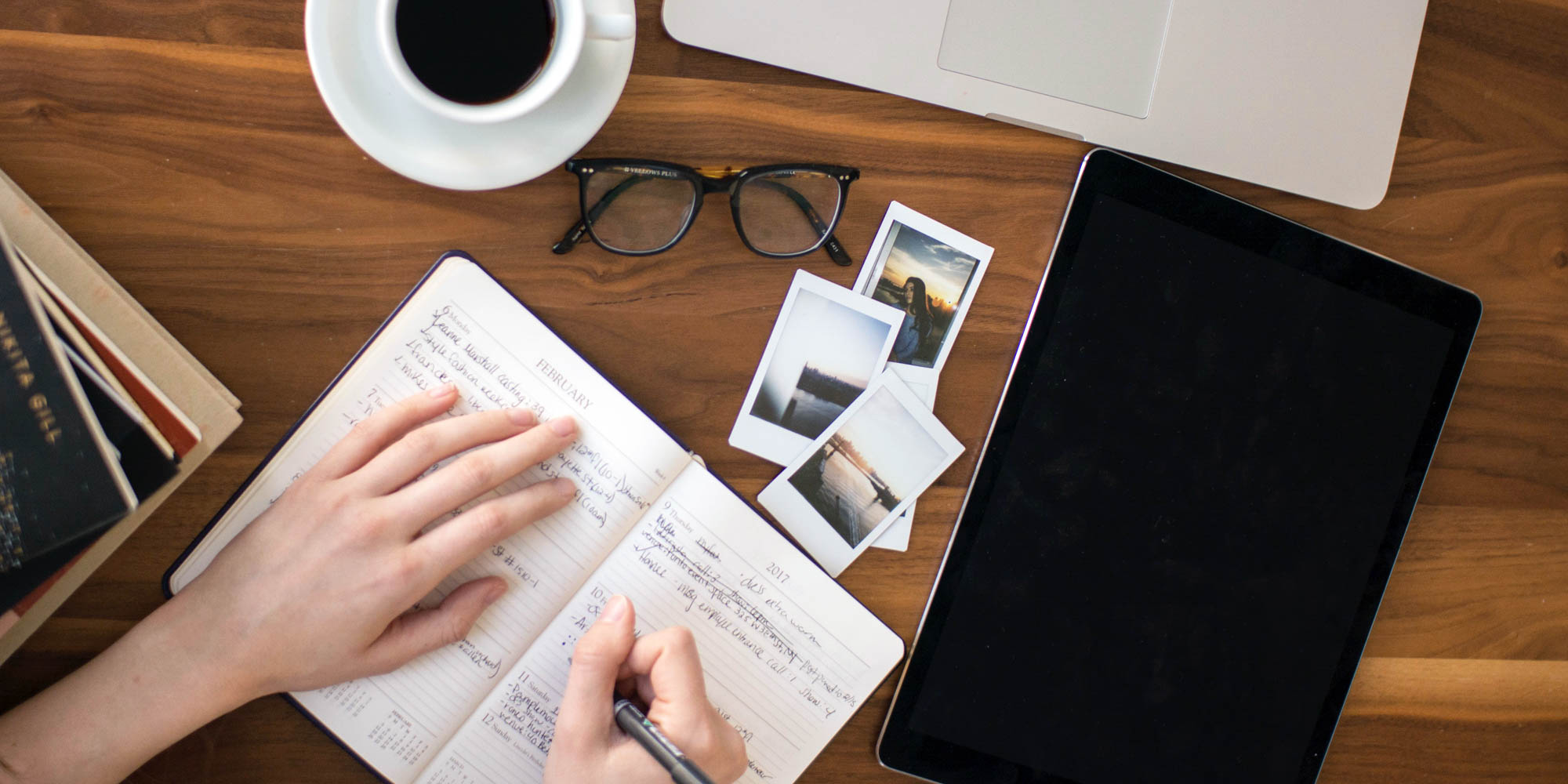 Person skriver kreativ tekst i notesbog ved et roligt arbejdsbord.