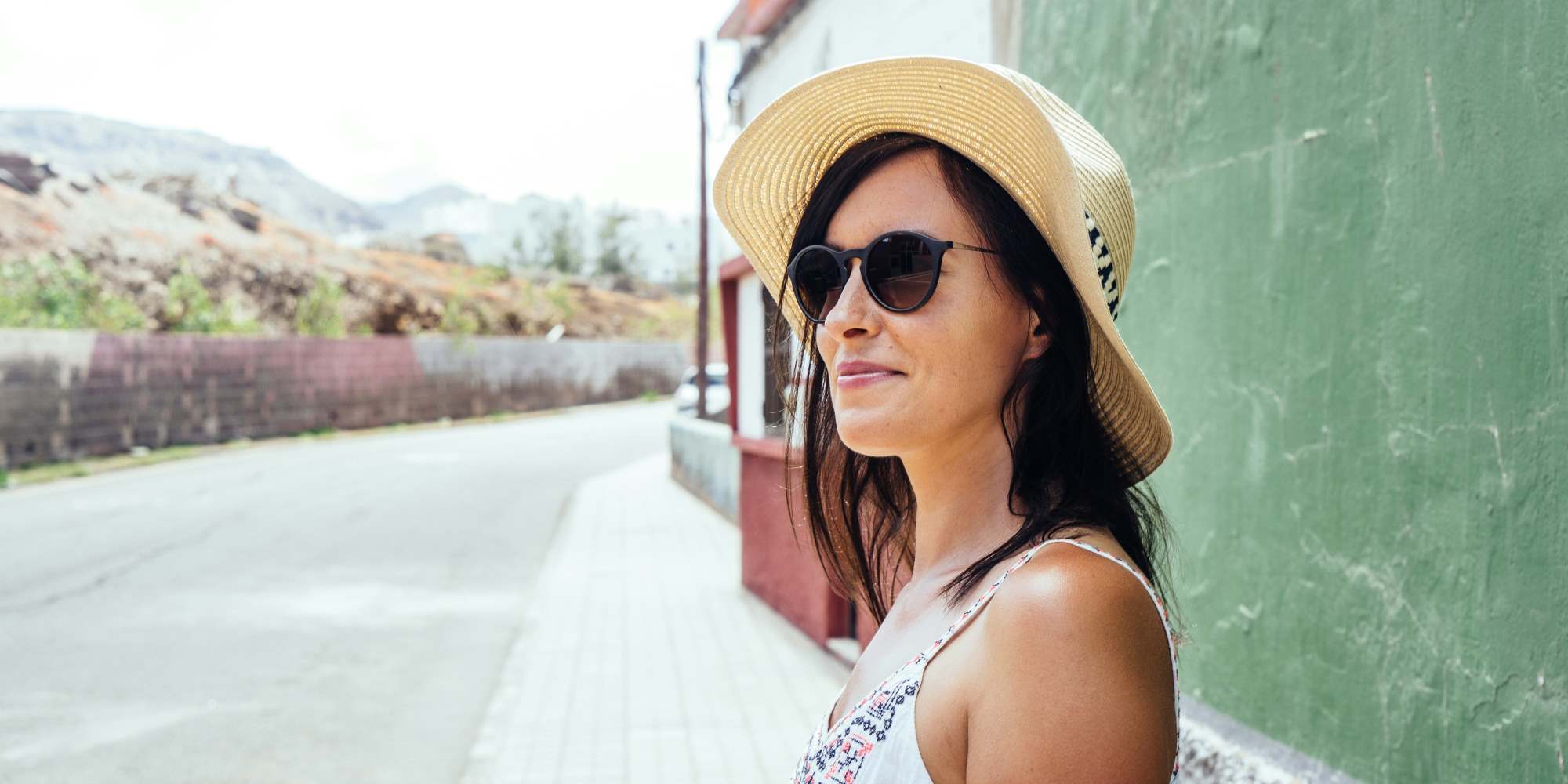 kvinde smiler med solhat og solbriller udenfor i Spanien