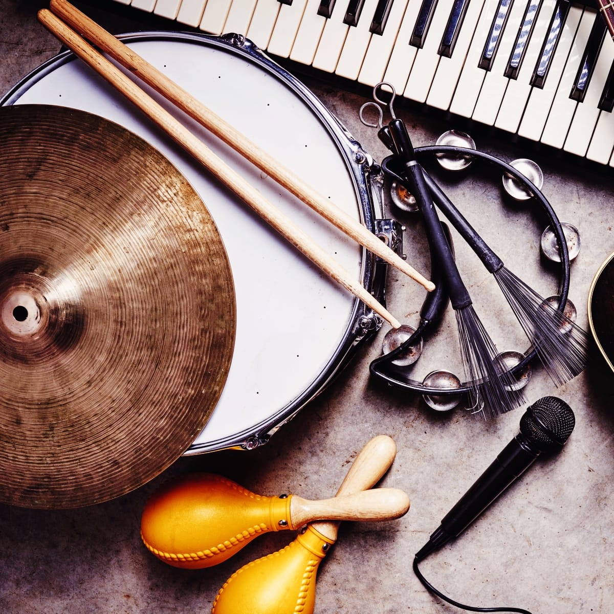 “Musikinstrumenter som tromme, bækken, tamburin, maracas, keyboard og mikrofon – symbol på musik og rytmik.”