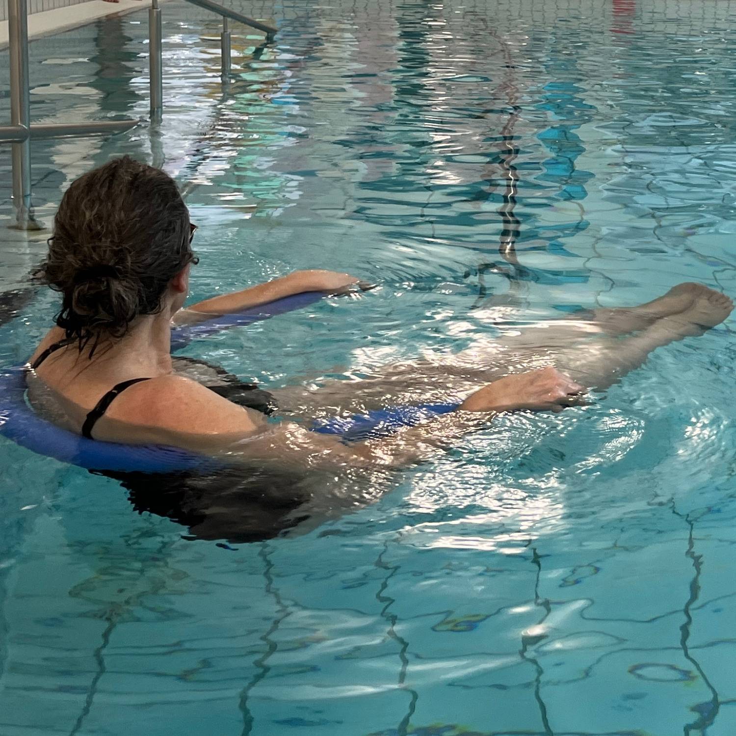 Kursist der flyder i et vandbassin i en svømmehal ved hjælp af en skumnudel