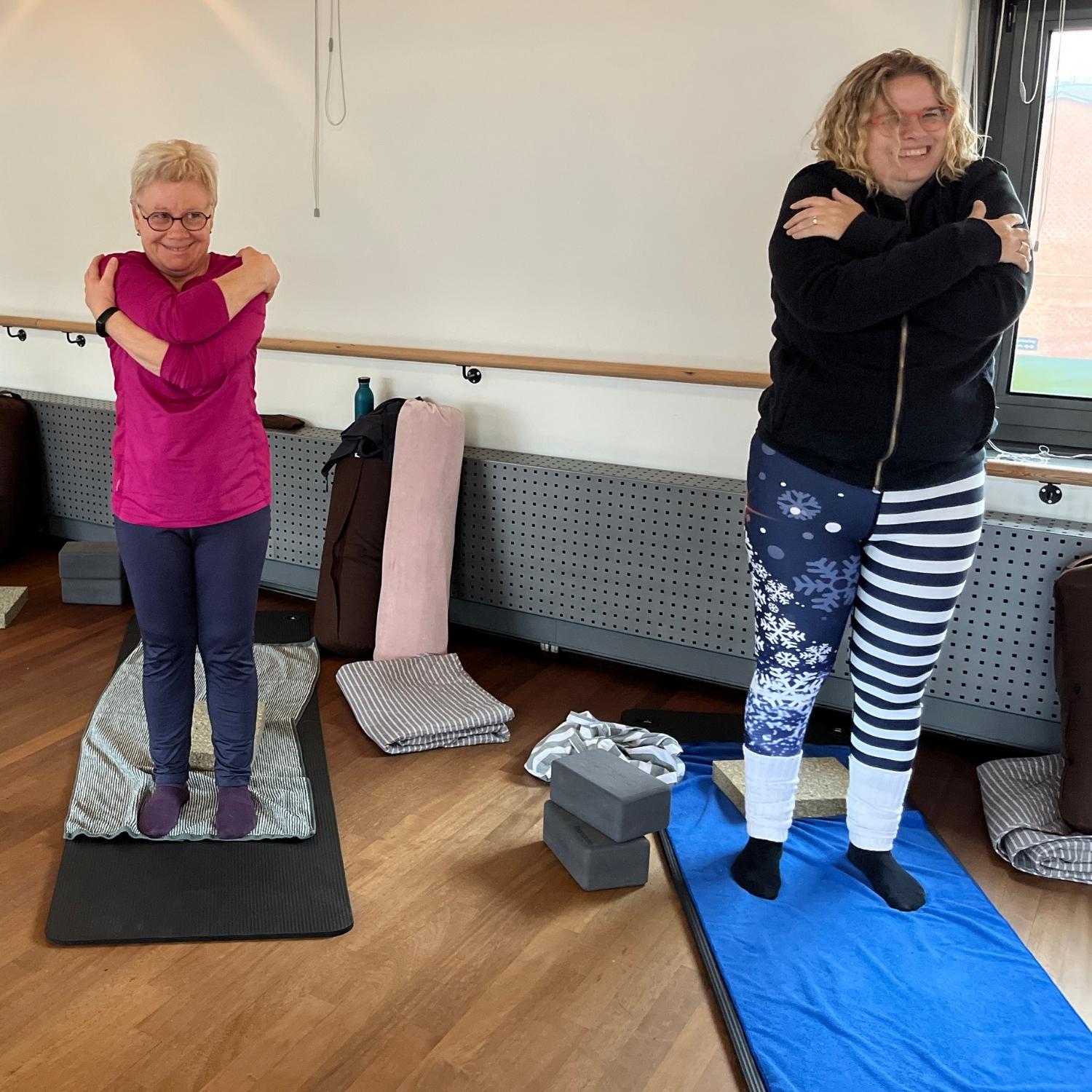 Kursister der laver yoga øvelser stående på yogamåtter