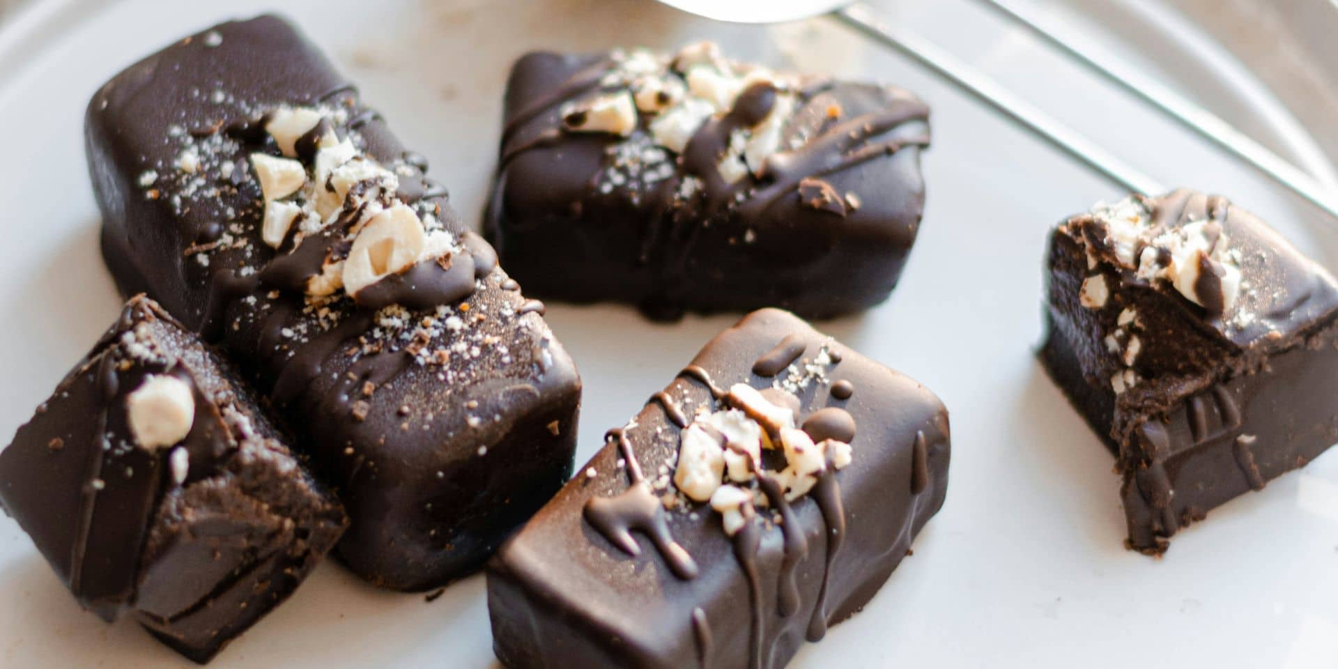 Julekonfekt. Tre stykker. Overtrukket med chokolade og drysset med nødder. Du kan lære at lave julekonfekt på dette madlavningskursus i FOF Aarhus.