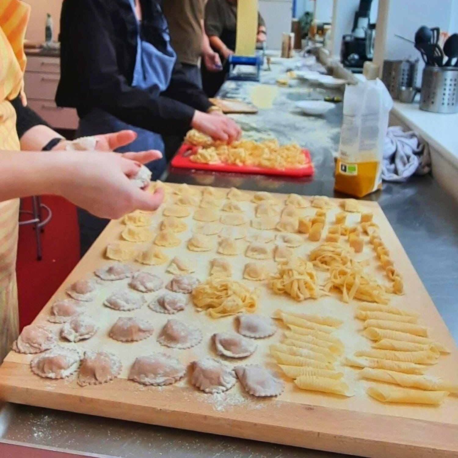 Kursister der former forskellige typer italiensk æggepasta ud på plader