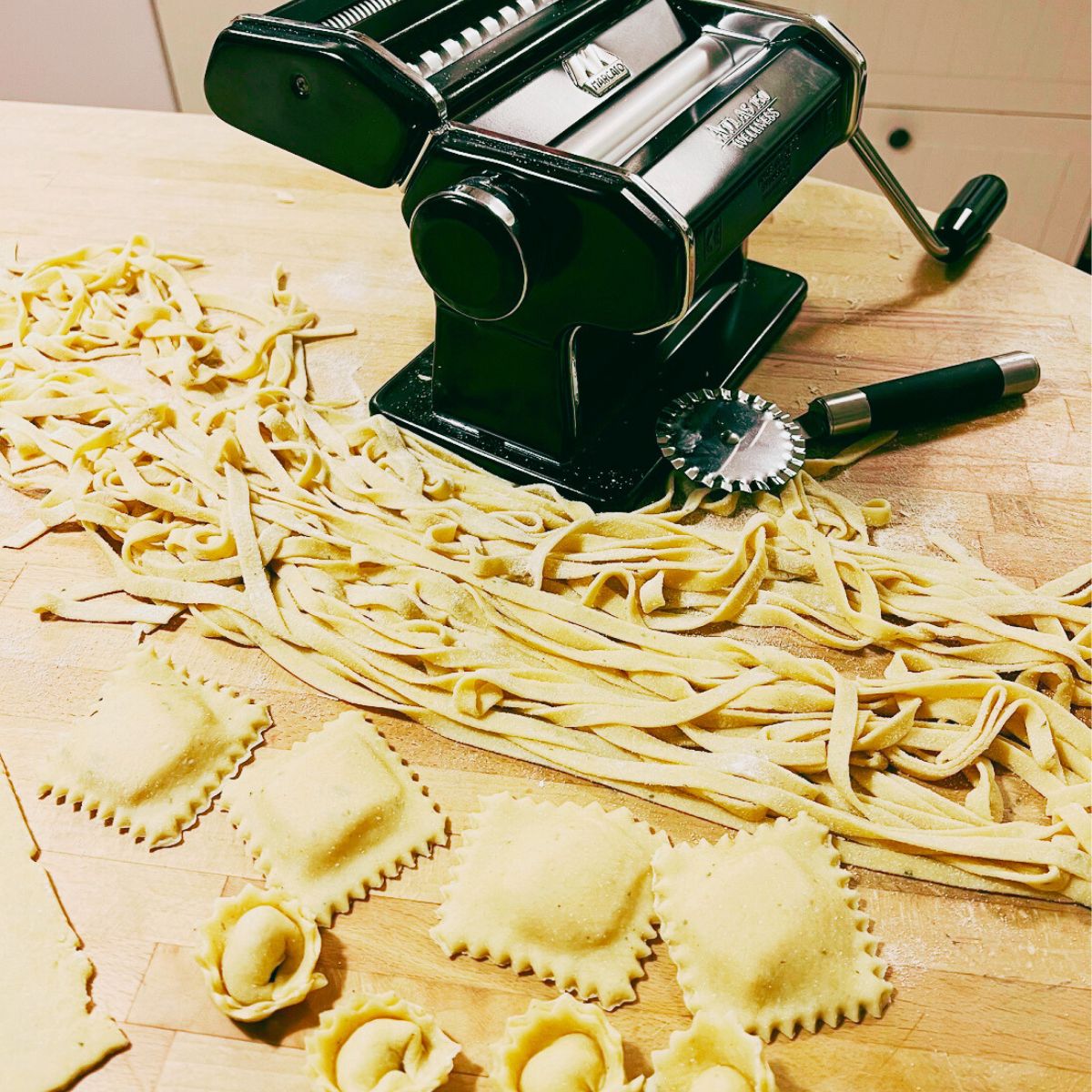 Deltager ruller frisk italiensk pasta ud med en pastamaskine under et madkursus