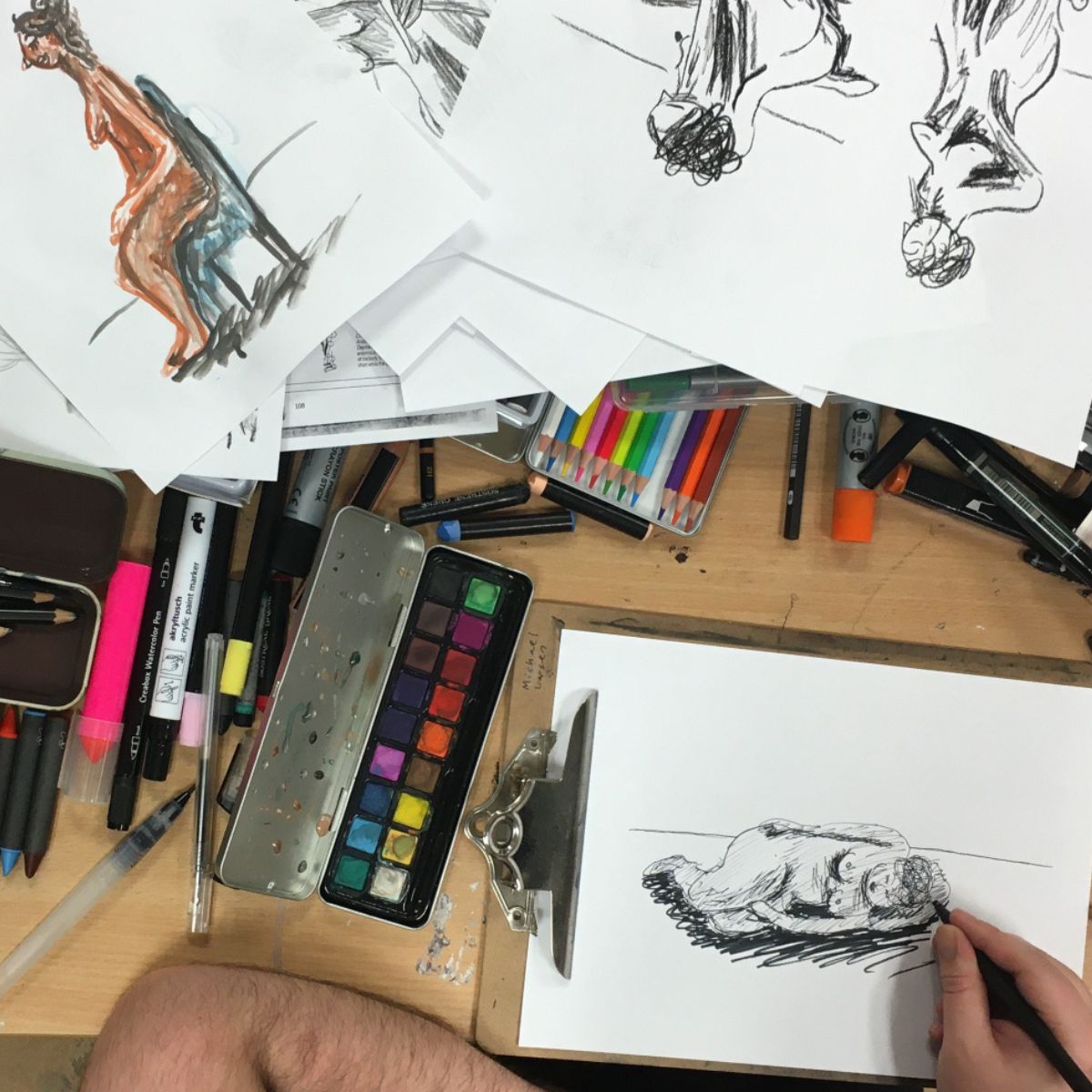 Croquis tegninger på et skrivebord med en masse skriveredskaber og farver