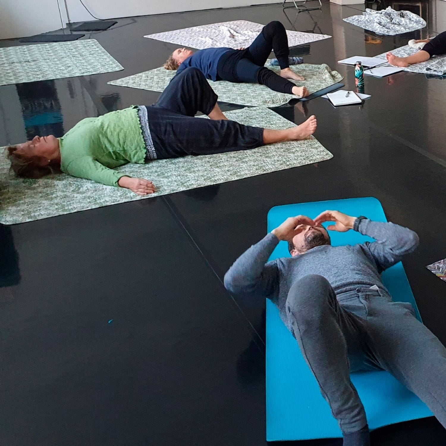 Kursister der laver Fascial Flow øvelse liggende på yogamåtter