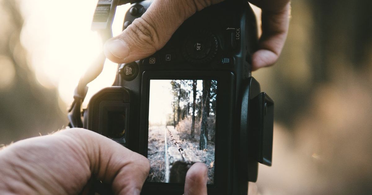Kursist fotograferer udendørs med digitalt kamera i naturligt lys.