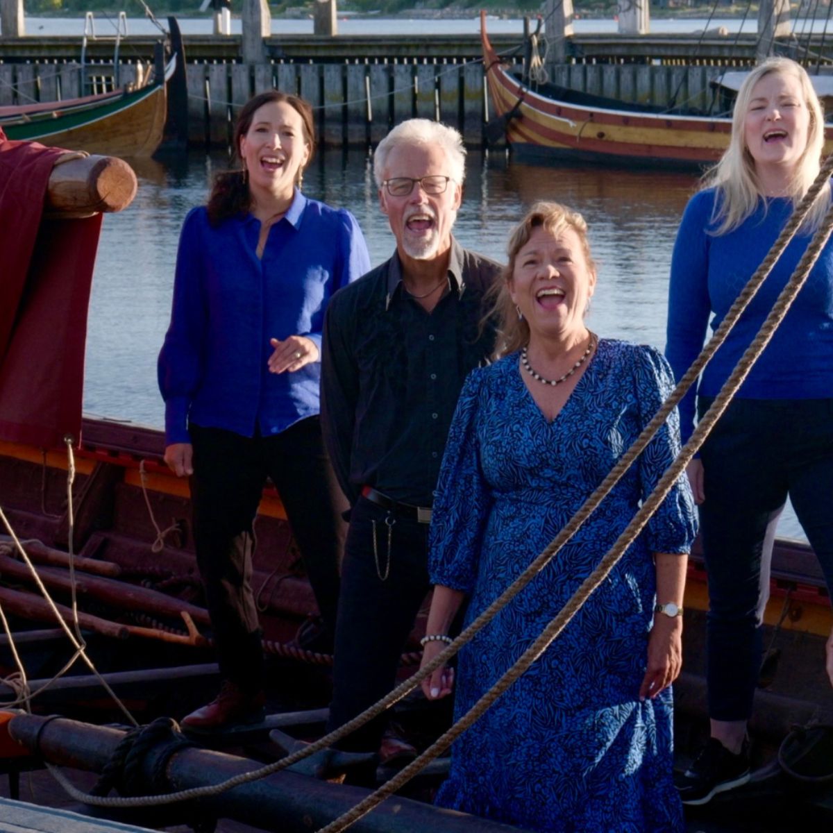 Korkor øver i Tåstrup Kulturcenter med klaver, sangere i alle aldre arbejder med harmonier og nodemateriale. Deltagerne smiler, griner og engagerer sig i musikken under dirigentens vejledning.