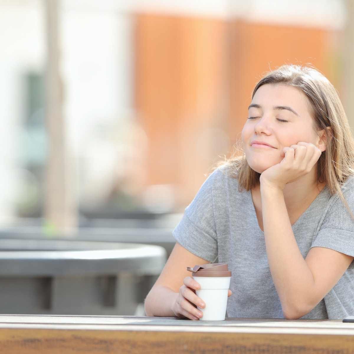 Kvinde slapper af med lukkede øjne og en kaffekop