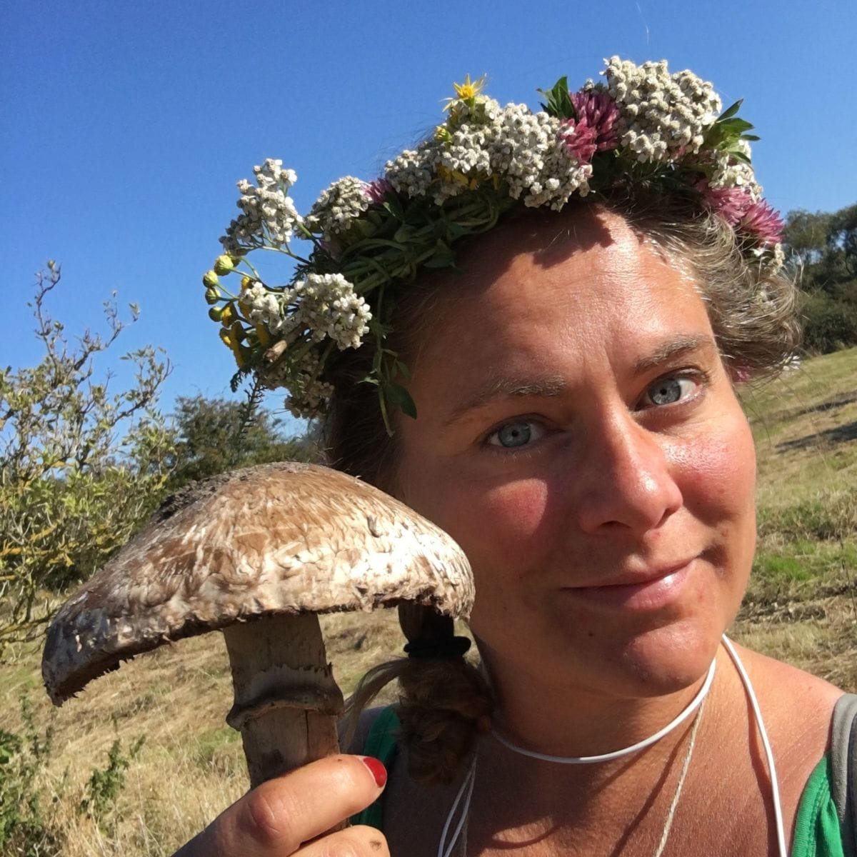 Underviser står med stor svamp i hånden og blomsterkrans på hovedet