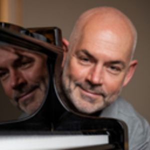 Nicolaj Holmboe smiler ved klaveret – musikalsk foredragsholder