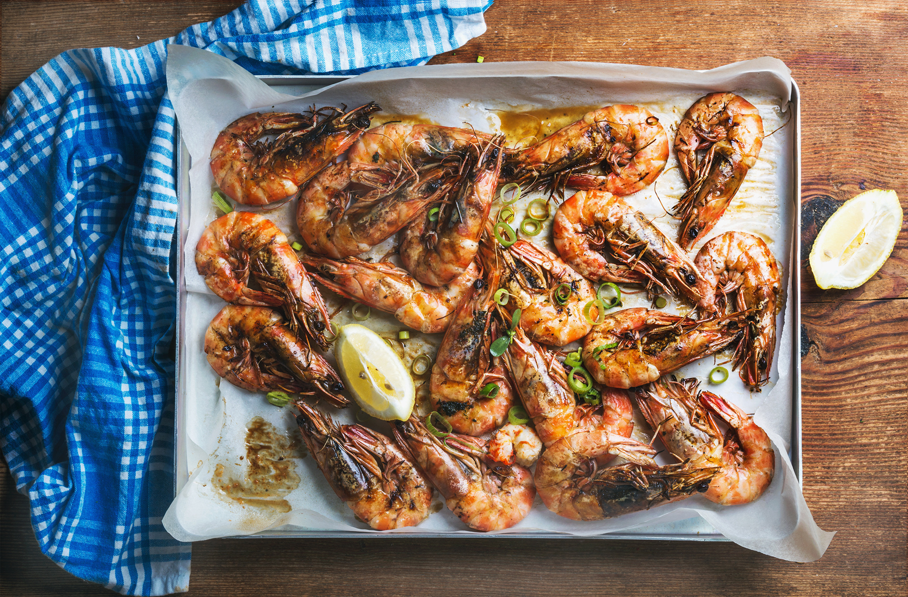 Grillede rejer anrettet på fad med citronskiver og forårsløg