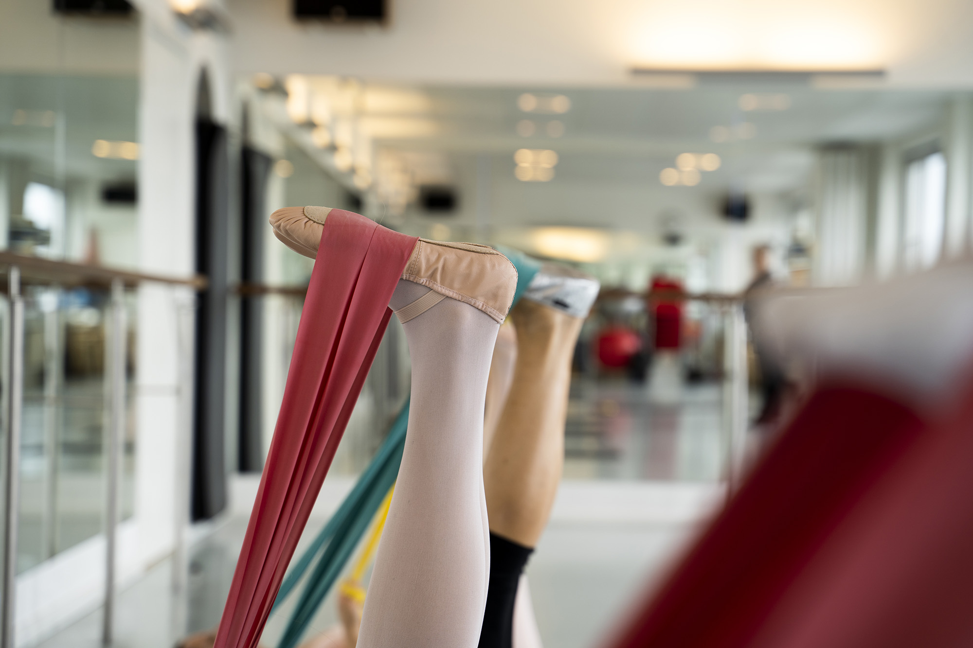 Letøvede kursister ligger på gulvet og træner fleksibilitet med foden i gummibånd hos FOF København og Nordsjælland