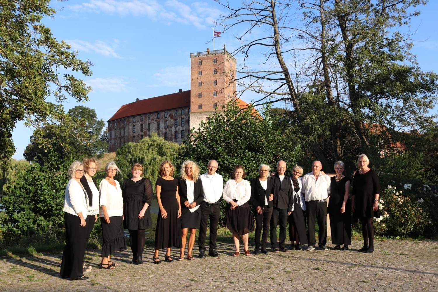Kolding Kammerkors medlemmer med Koldinghus i baggrunden ved Slotssøen i Kolding