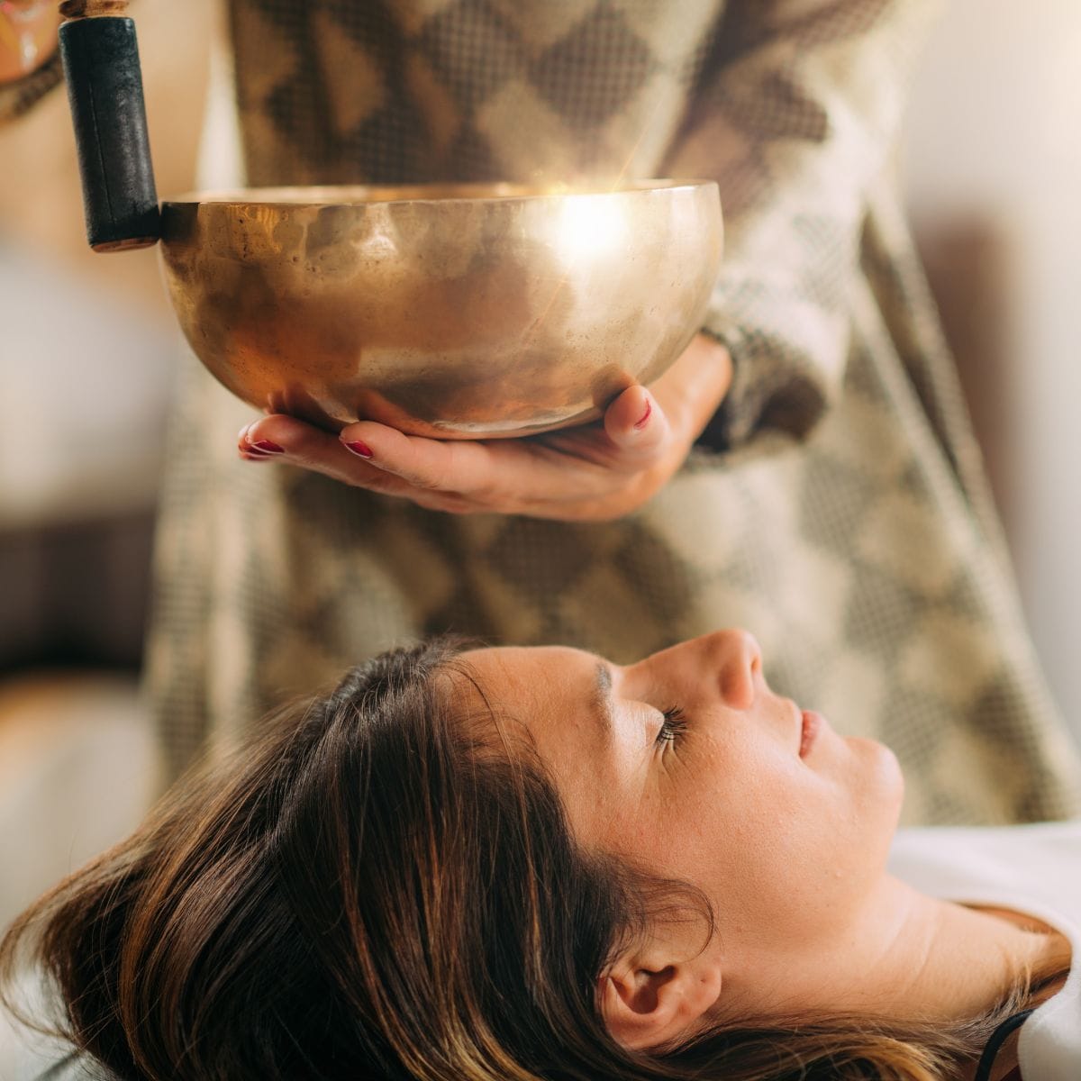 Personer ligger afslappet på måtter med tæpper, mens klangskåle skaber rolig stemning