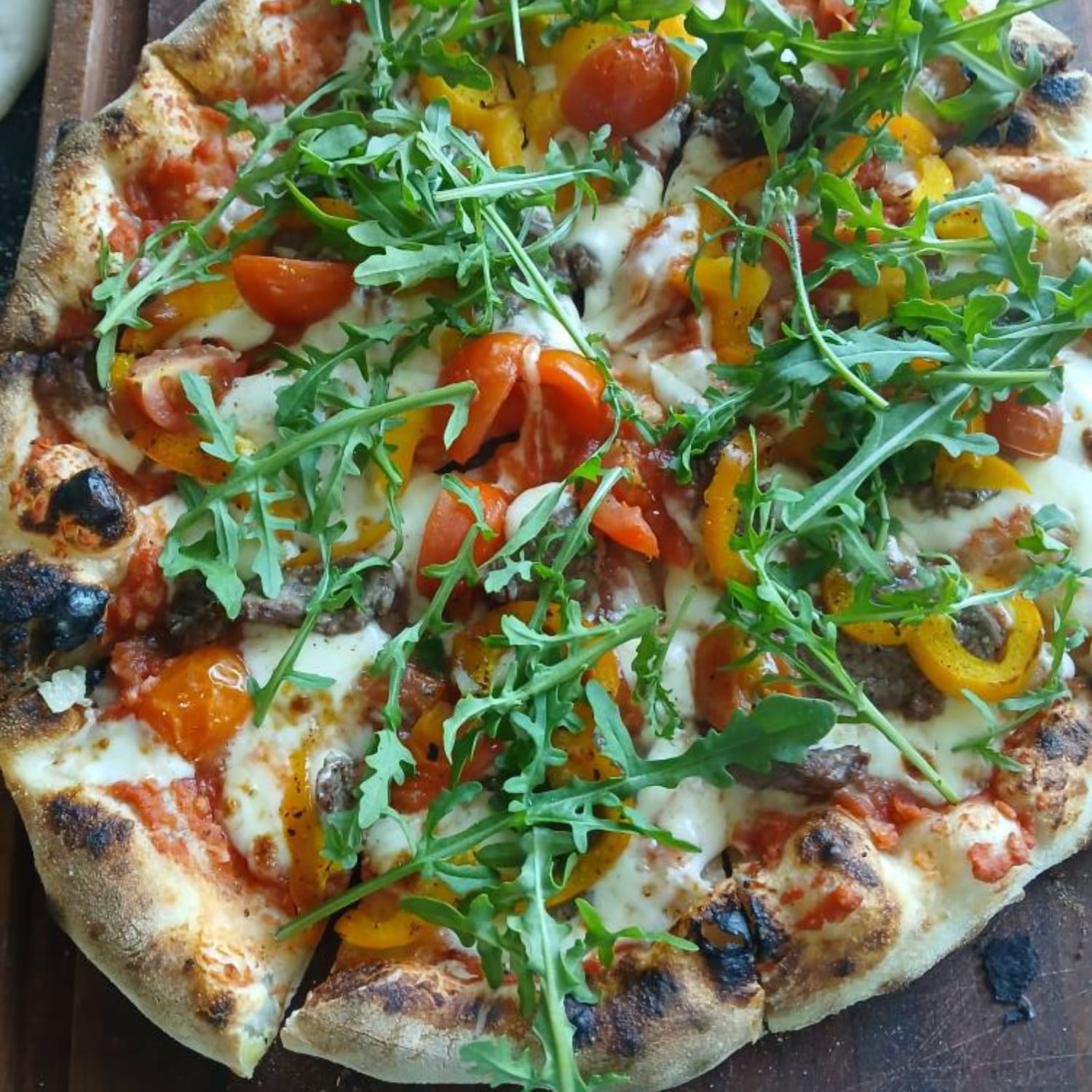 Hjemmelavet pizza med oliven, ruccola, gul peber, osv.