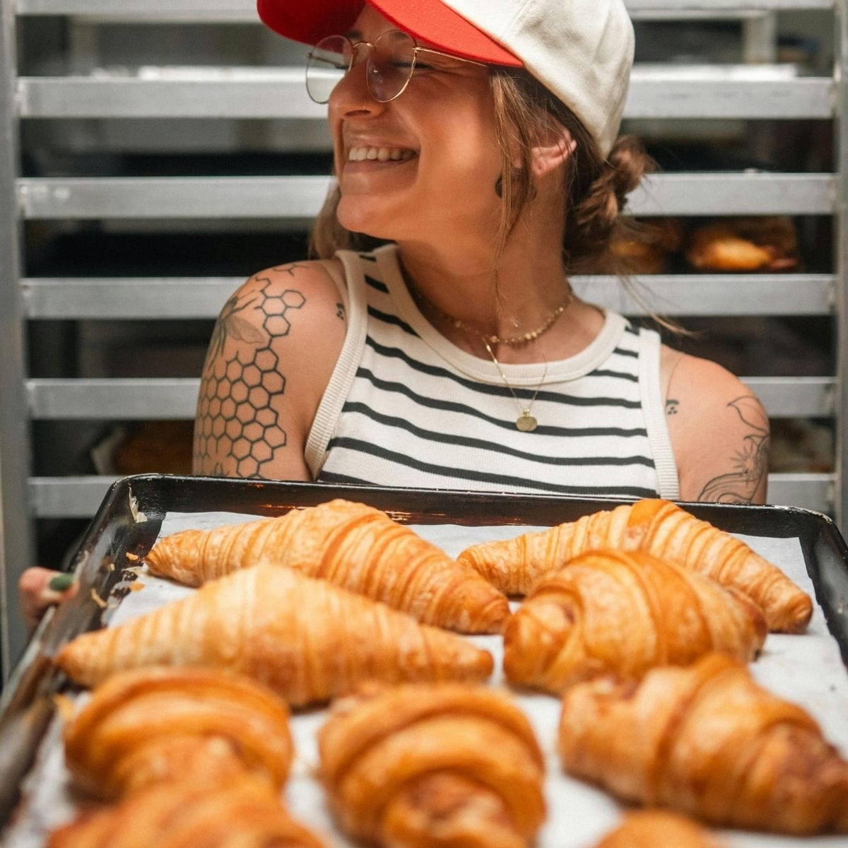 Kvinde står med en bradepande med nybagte croissanter