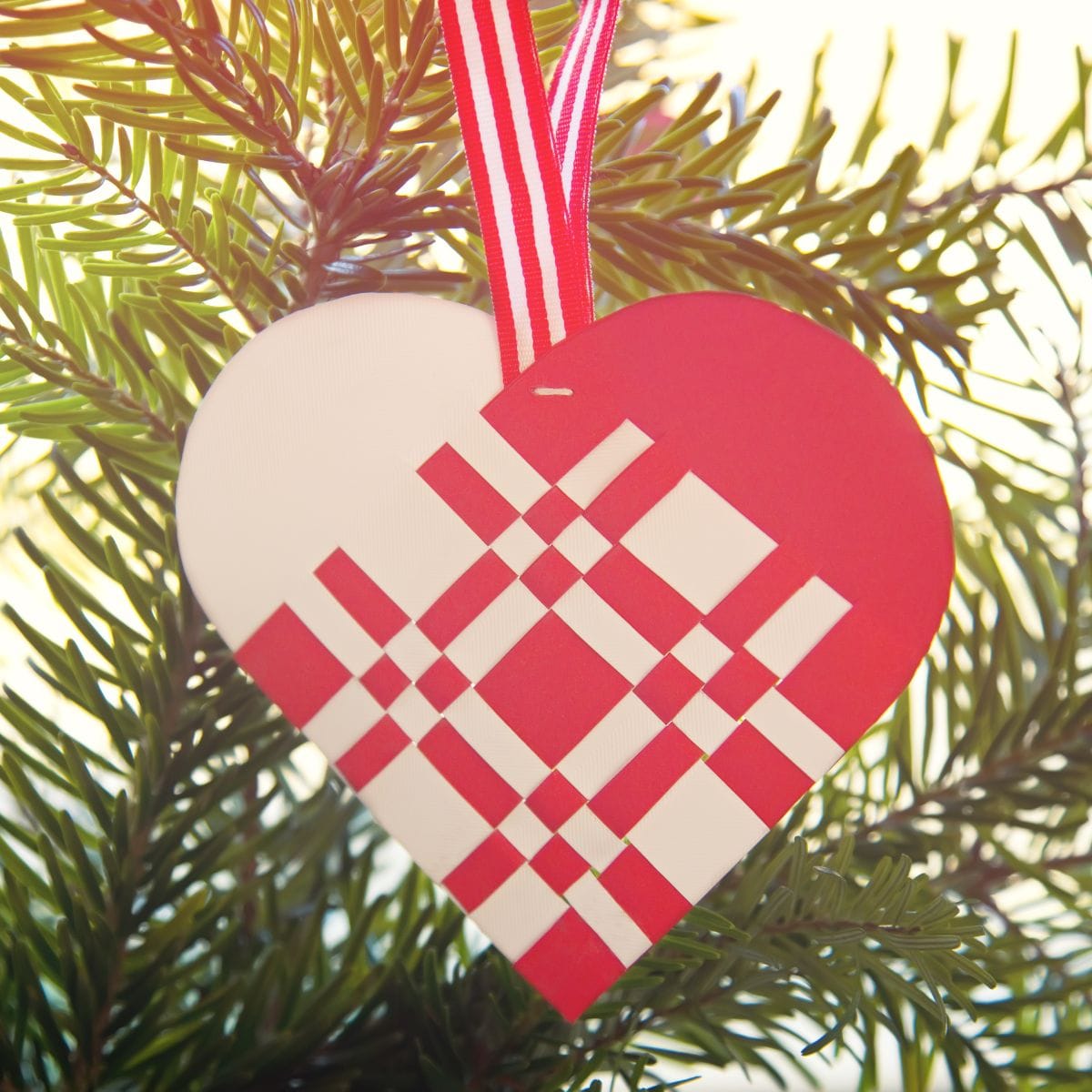 Et klassisk flettet julehjerte i rødt og hvidt glanspapir.