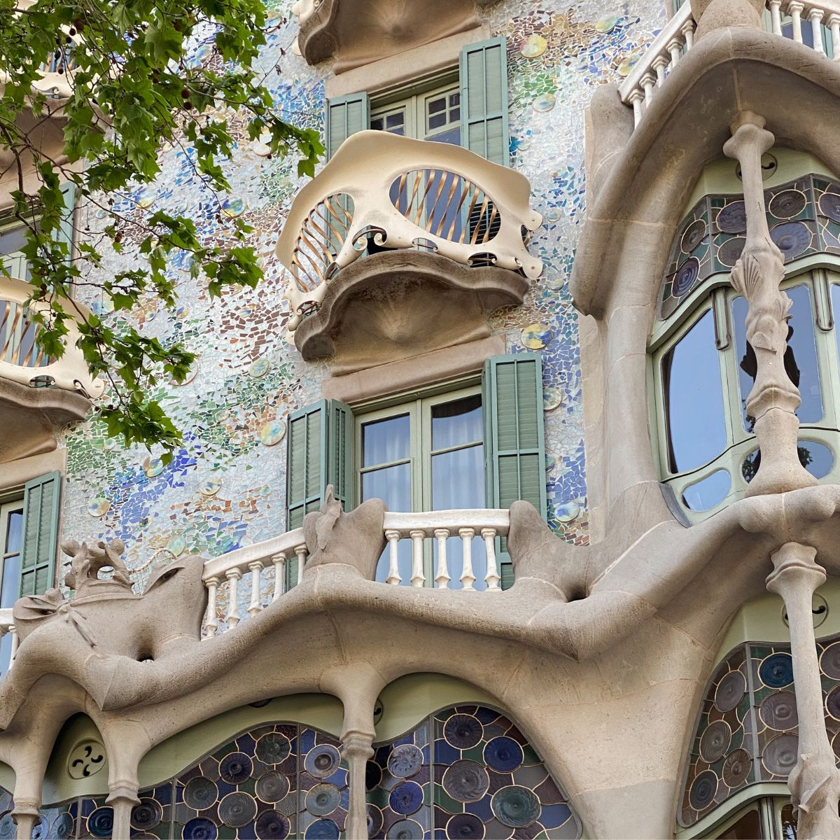 En gruppe voksne sidder rundt om et bord med spanske lærebøger og notesblokke. Læreren skriver på tavlen og deltagerne øver samtaler på spansk.