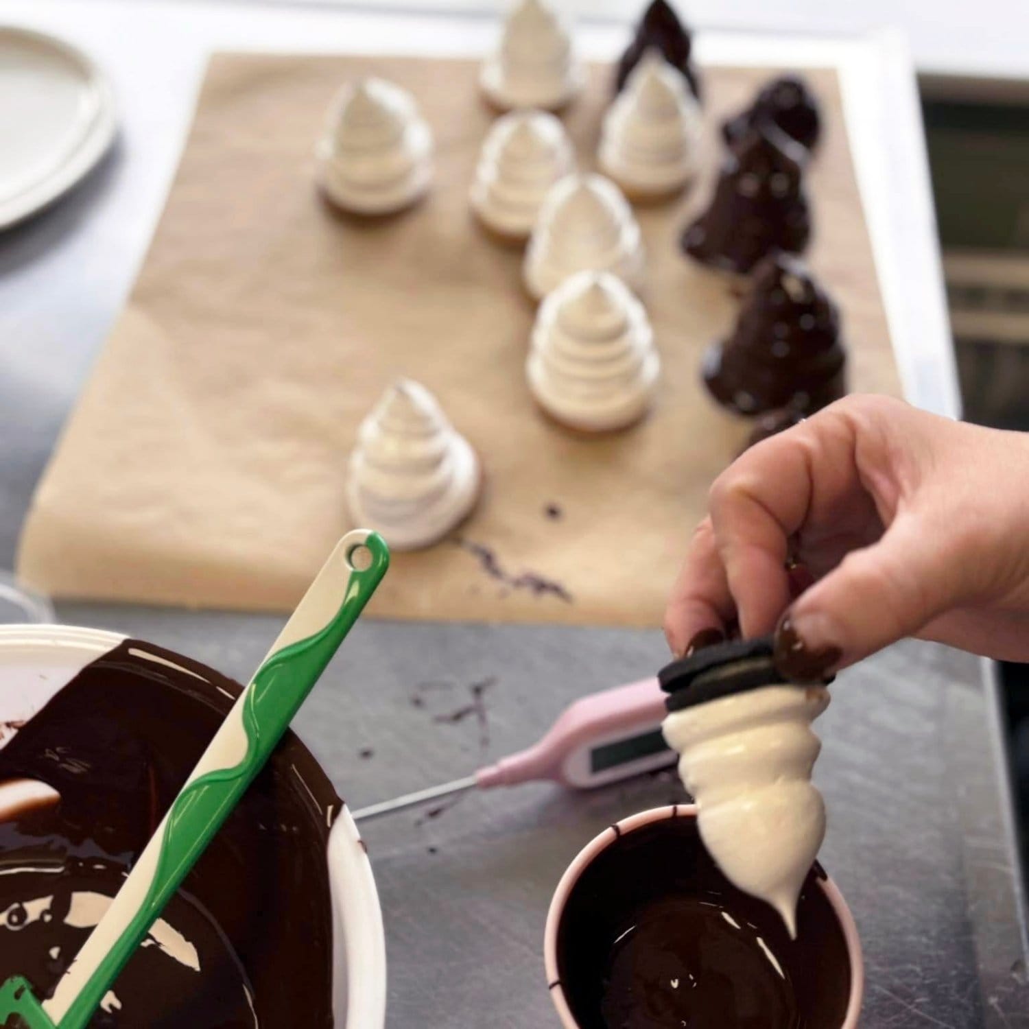 Flødeboller der er ved at blive dyppet/betrukket med mørk chokolade